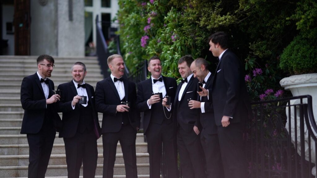 The groomsmen and groom richie head up the steps to the gallerie Veranda at Cabra Castle for the wedding ceremony