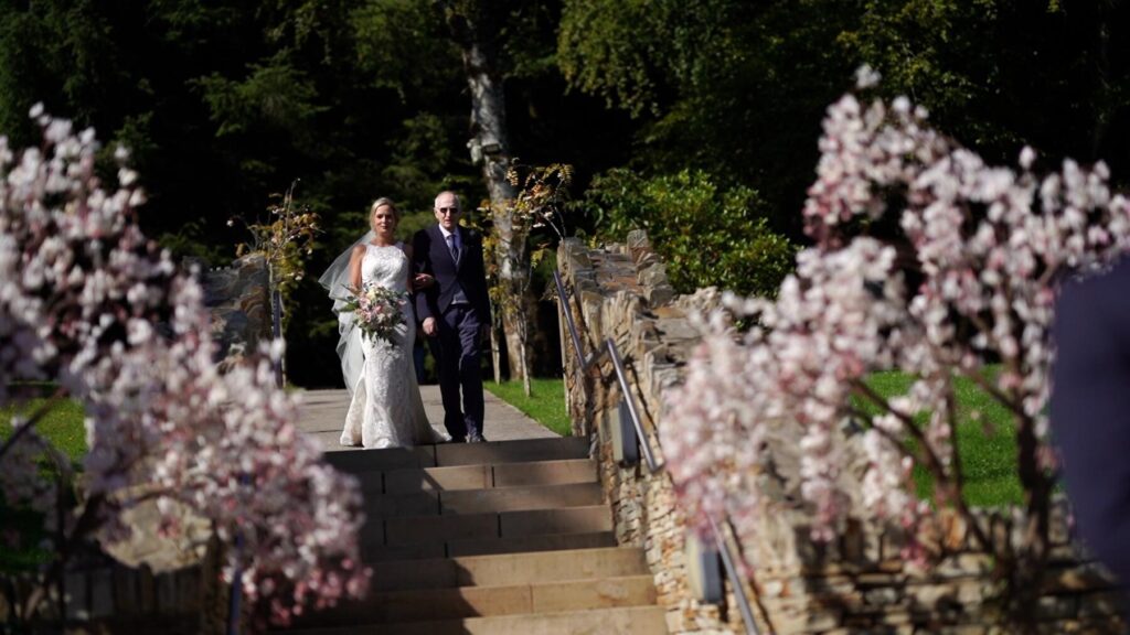 bride and father walk into outdoor wedding ceremony