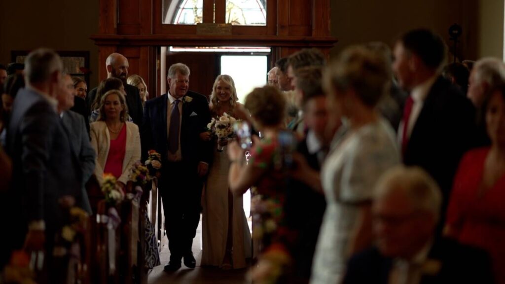 Bride and father walk up aisle in a still image from the virginia park lodge wedding video